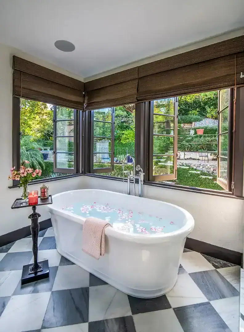  A marble checkerboard floor adds drama in the primary bathroom that opens up to the back terrace. Photos by  Nolasco Studios.  