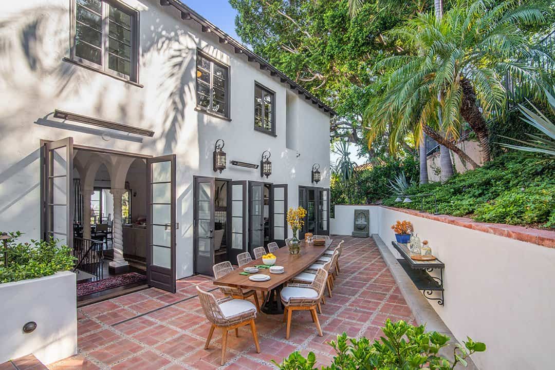  The back terrace holds a custom Cedar dining table and dining chairs by Palecek. Photos by  Nolasco Studios.  