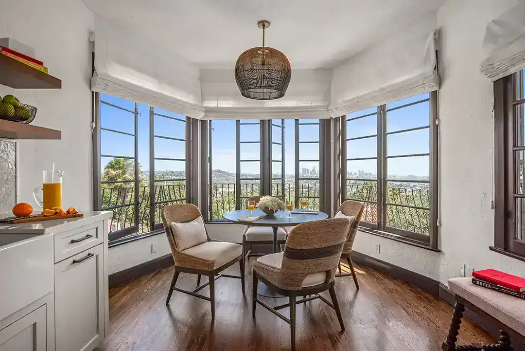  In the breakfast room and kitchen the dining table is by RH, the dining chairs and island stools are by Palecek and the pendant fixture is from Arteriors. Photos by  Nolasco Studios.  