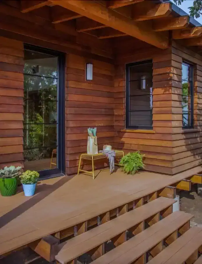   Reclaimed wood graces the exterior and wraparound deck of the ADU, which is surrounded by native landscaping.   