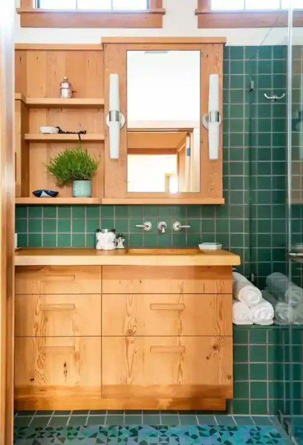   Green tiles complement an oversized vanity in the bathroom, which gets a lot of natural light.   